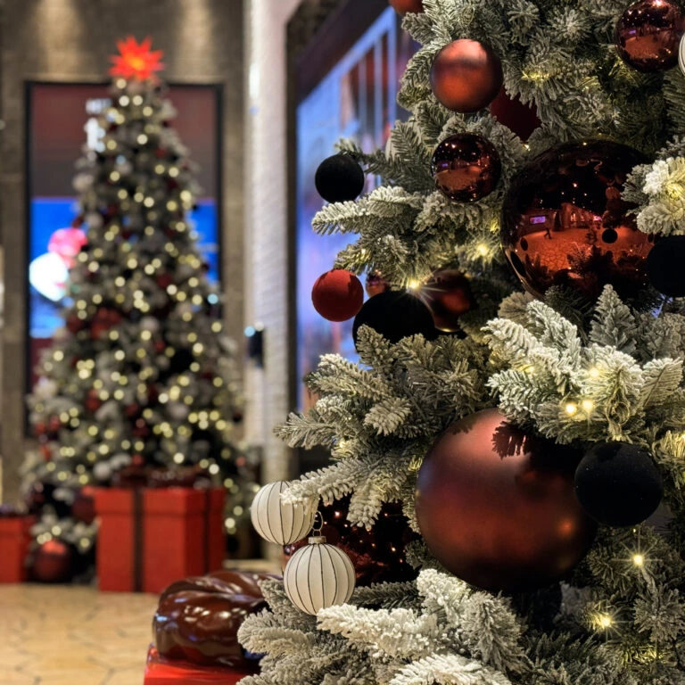 Buy snowy Christmas tree with red ornaments and fairy lights for home or commercial decoration.