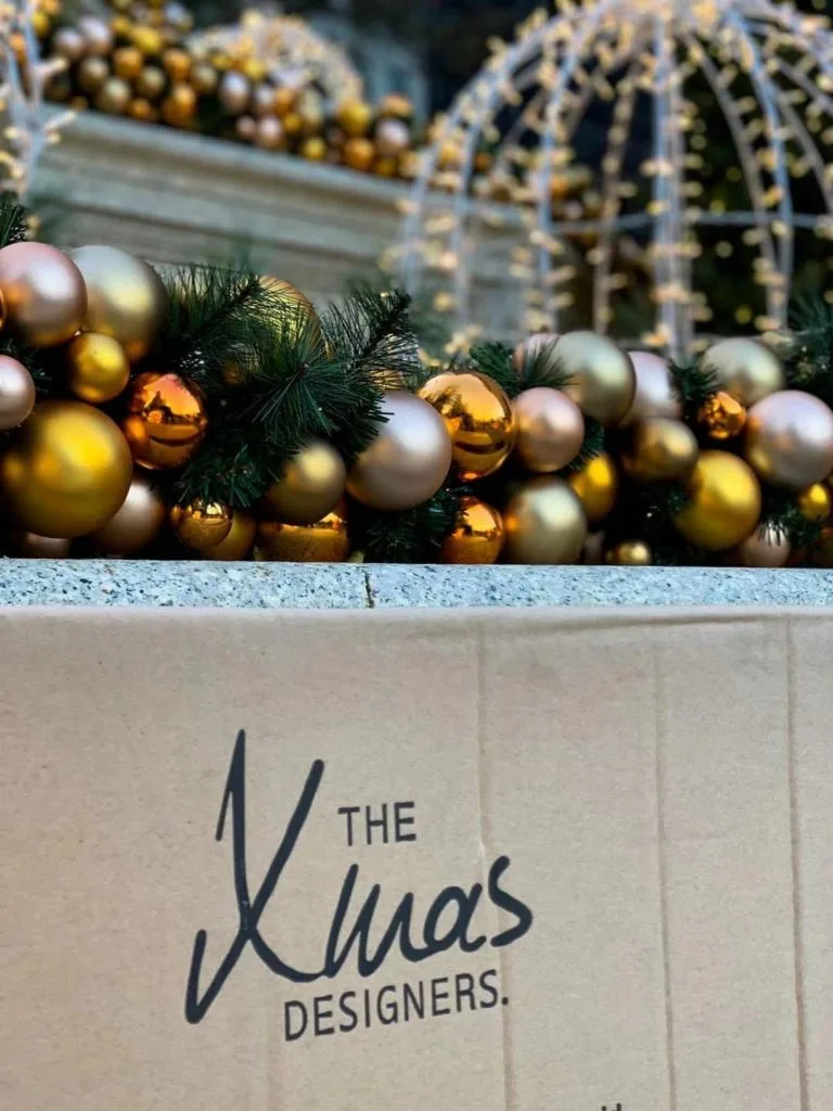 Shop outdoor Christmas garland with gold ornaments and greenery for luxury hotel entrances.