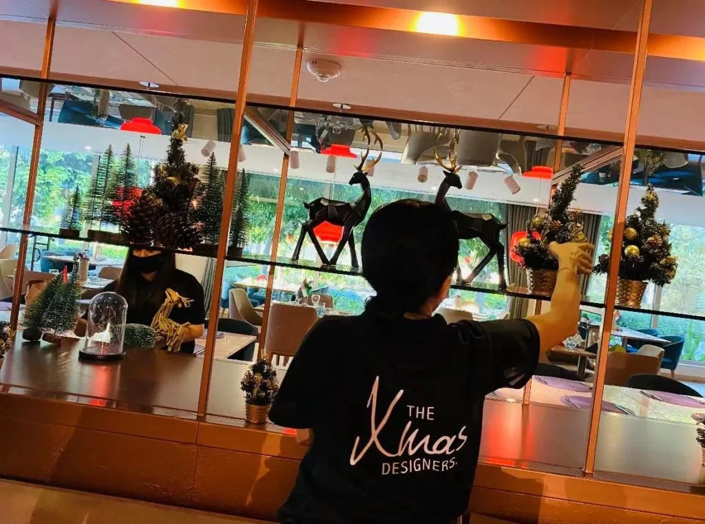 Designer setting up premium customised Christmas decorations with reindeer and pine trees, highlighting exclusive festive styling and attention to detail.