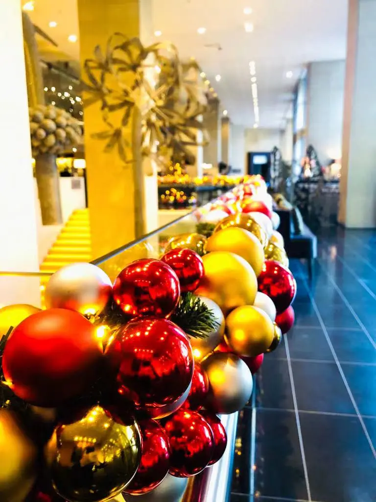 Fully decorated luxury Christmas tree with sparkling red and gold ornaments in a hotel lobby, featuring the best Christmas decorations Dubai and premium customised festive decor.