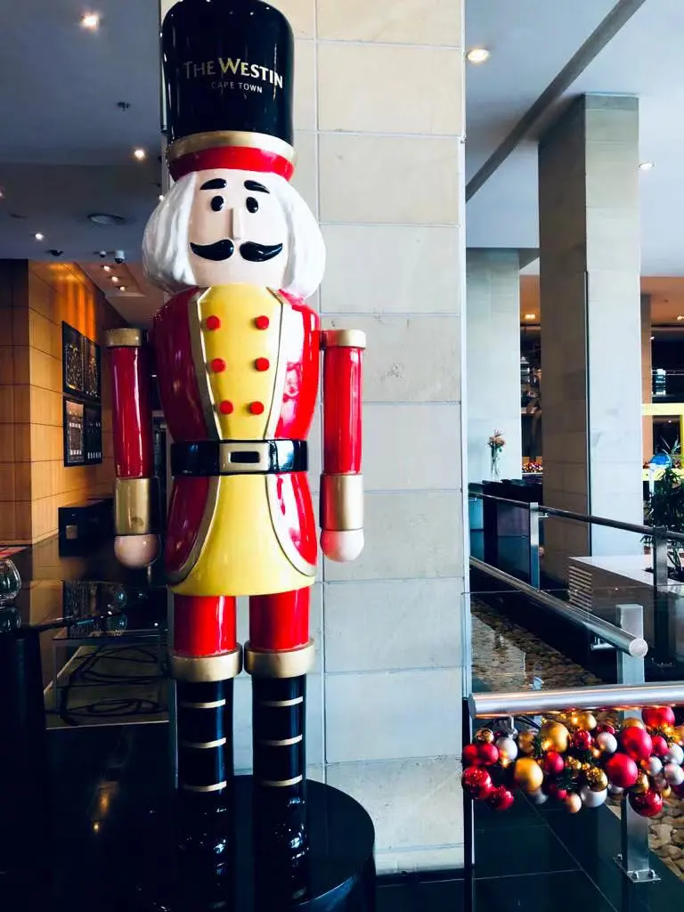 Professional decorators arranging a grand Christmas tree with red and gold ornaments, highlighting quality Christmas decor and bespoke festive styling.