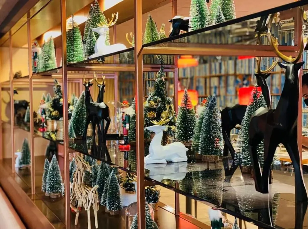 Elegant Christmas shelf display featuring luxury reindeer figurines and mini snow-covered trees, styled with bespoke holiday decorations for a sophisticated interior.